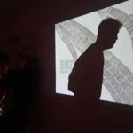 Pengunjung berjalan di depan salah karya visual yang dipantulkan ke dinding pada pameran Mutuals "Garis Mencurigakan" di Galeri Marlah Hub di Palu, Jumat (1011/7/2025). (bmzIMAGES/basri marzuki)