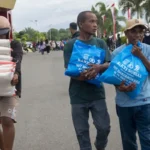 Warga membawa paket sembako yang dibagikan pada Semarak Bahayangkara di Mapolda Sulteng, Kamis (3/7/2025). (bmzIMAGES/Basri Marzuki)