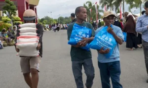 Warga membawa paket sembako yang dibagikan pada Semarak Bahayangkara di Mapolda Sulteng, Kamis (3/7/2025). (bmzIMAGES/Basri Marzuki)