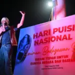 Seniman Arifin Sunusi mendeklamasikan puisinya dalam perayaan Hari Pusi Nasional di depan Kantor DPRD Sulteng, Sabtu (2/8/2025) malam. (©bmzIMAGES/basri Marzuki)